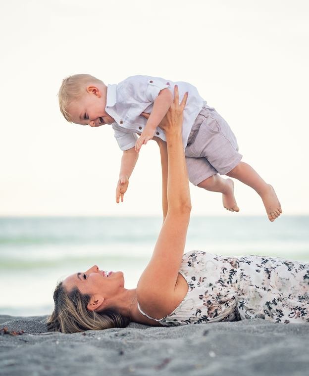 Mother lifting her baby at sunset