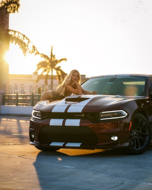 Glamour portrait on the hood of a muscle car at sunset